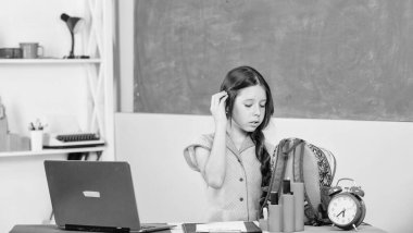 Bilgisayarlı küçük bir kız öğrenci. Yeni teknolojiyi kullan. Okula dönüyorum. Online eğitim. Evde eğitim kavramı. İyi sabahlar. İnternet üzerinden çalış. Ders alarmı. Sınıfta saati olan bir kız Gün sonuna kadar bekler