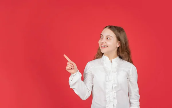 Anúncio importante. menina adolescente com rosto feliz apontando o dedo no espaço de cópia. voltar para a escola. — Fotografia de Stock