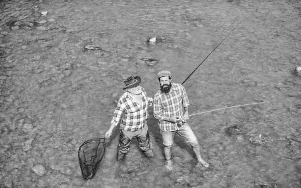 Birlikte paylaşmak. Baba oğul balık tutuyor. Hobi ve spor aktiviteleri. Alabalık yemi. Erkek arkadaşlığı. Aile bağı. Elinde olta ve ağla iki mutlu balıkçı. Yaz haftasonu. Olgun erkek balıkçı — Stok fotoğraf