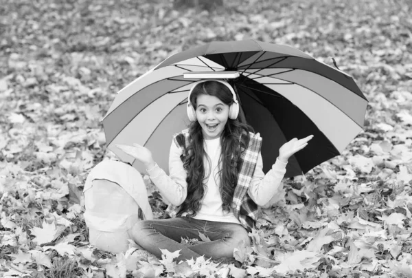 Tillbaka till skolan. Internetutbildning. Säsongsväder. Glad unge bär hörlurar under paraply. flicka lyssna musik med bok. barn koppla av i höstskogen. faller löv i parken. Viktig del av campingen — Stockfoto