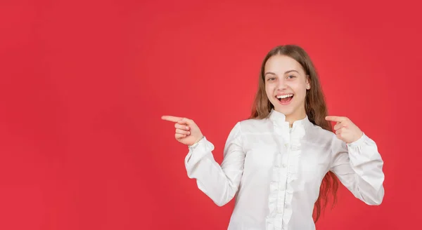 Menina adolescente com rosto feliz apontando o dedo no espaço de cópia. de volta à escola. conceito de publicidade. — Fotografia de Stock