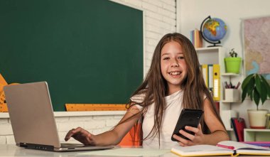 Mutlu bir gün. Çocukluk gelişimi. İnceleme yoluyla bilgi edinmek. Sınıfta tahtası olan bir çocuk. Çocuk bilgisayarı kullanıyor. Okula dönüyorum. Modern hayatta çevrimiçi resmi eğitim. evde eğitim kavramı