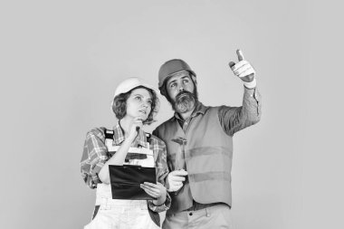 Tadilat için aile hesapları. Yuvanın yenilenmesi. Yenileme konsepti. Çift planlama yenileme dairesini değiştirir. Belgelere bakan bir çift. Kadın ve erkek emniyet kaskı takıyor