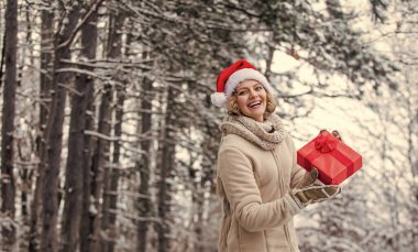 Kış tatili konsepti. Kış hediyesi. Noel 'i kutlayalım. Kadın sıcak giysileri, karlı orman. Doğa karla kaplı. Kış kıyafeti. Yeni yıl. Mutlu noeller. Boks günü. Kız kırmızı hediye paketi tutun
