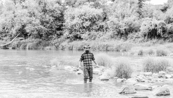 Fisher fishing equipment. Rest and recreation. Fish on hook. Brutal man  stand in river water. Man bearded fisher. Fisher masculine hobby. Fishing  requires to be mindful and fully present in moment Stock