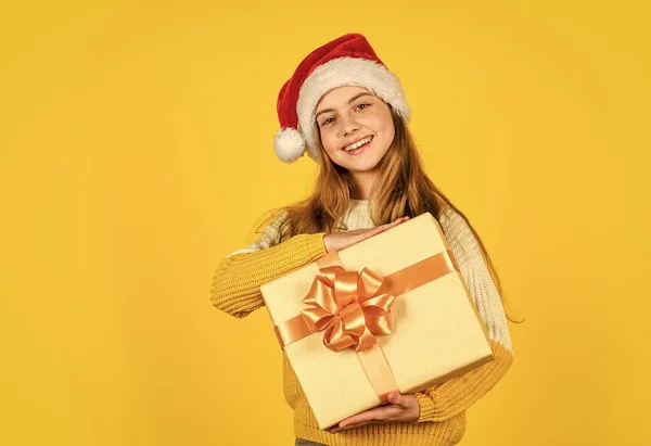 Niña santa en el fondo amarillo. fiesta de Navidad celebración. Feliz año nuevo. compras de Navidad en línea. tiempo para el descuento. Sonriente chico mantenga la compra. regalos y regalos de santa claus —  Fotos de Stock