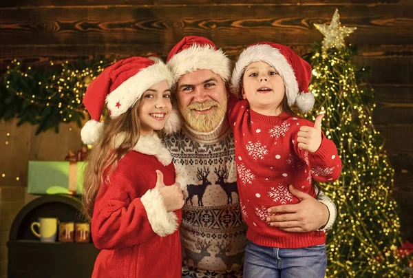 Por Dios, sé alegre. Papá e hijas decoran el hogar. Papá Noel barbudo con niños. Luces del árbol de Navidad. invierno perfecto. Se acerca el año nuevo. familia feliz celebrar la Navidad. niñas pequeñas aman a su padre —  Fotos de Stock