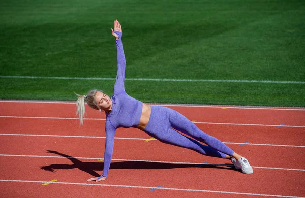 Sexy mujer deportiva estiramiento y calentamiento en ropa deportiva en pista de atletismo estadio, estilo de vida saludable — Foto de Stock