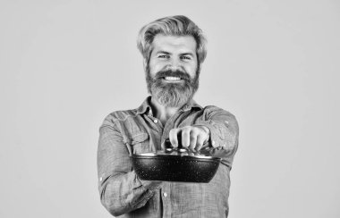 Yapışmaz tava porseleni yüzeyi. Adam yeni bir tava aldı. Sağlıklı yemek pişirmek. Sakallı hippi kahvaltı hazırlıyor. Kızartma ipuçları. Mutfak gereçleri. Mutfak aletleri. İsimsiz dökme demir pişirme kapları