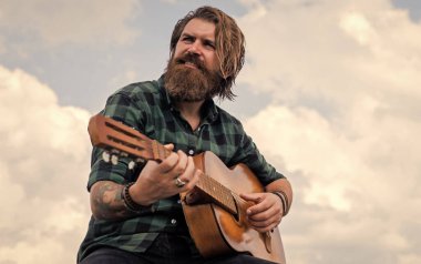 Pop müzik. müzik teli enstrümanı. Olgun karizmatik erkek gitarist. Sakallı ve bıyıklı adam gitar çalıyor. Kareli gömlekli sakallı adam şarkı söylüyor. Müzisyen