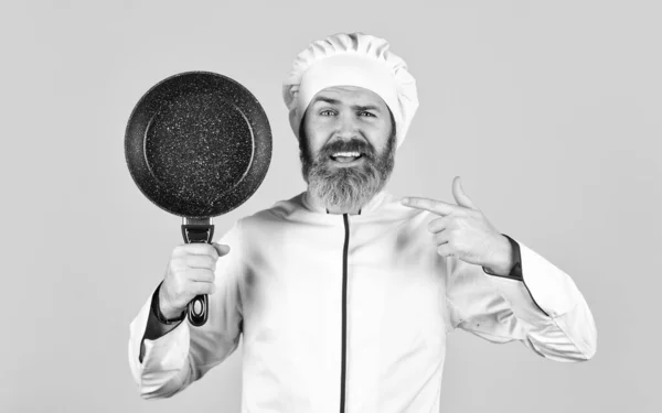 Professional kitchenware. Bearded chef preparing breakfast. Nonstick pan for frying. Enameled cooking vessels. Man hold pan. Nonstick cookware. Frying without oil. Frying meal. Healthy food — Stock Photo, Image