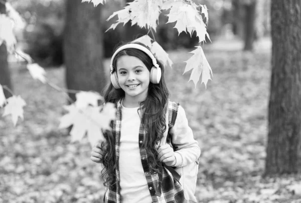 Okul çantalı kulaklıklı kız. Çocuk sonbahar parkında müzik dinler. Sonbahar çalışma zamanıdır. Okula dönüyorum. Online eğitim kavramı. Sonbahar yaprakları olan bir çocuk. — Stok fotoğraf