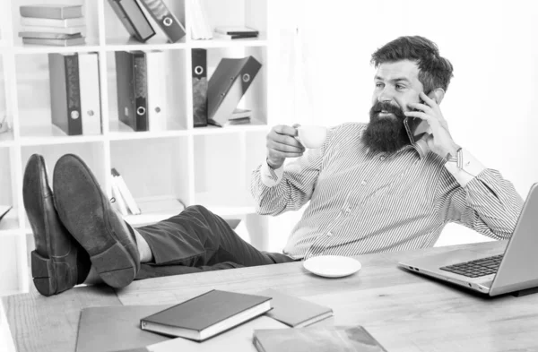 Лучший способ общения с клиентами. Бородач разговаривает по телефону, пьет чай. Коммуникации. 3G. 4G. Новые технологии. Мобильный телефон — стоковое фото