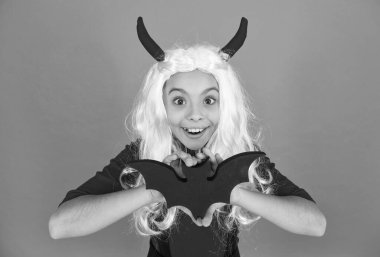 Cadılar Bayramı 'nda cadılar bayramı şapkalı komik çocuk ve turuncu arka planda yarasa tutan peruk, Cadılar Bayramı canavarları.