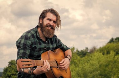 Tişörtlü, beyaz, vahşi hippi akustik gitar çalıyor.