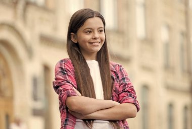 Mutlu bakışlı, kendine güvenen bir çocuk. Kollarını açık havada, moda tarzında çapraz tutuyor. Kendine güveniyor.