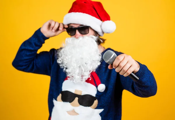 Feliciteer zijn naasten. Kerstliedjes. Kerstmis winkeltijd. Cadeaus en cadeaus voorbereiden. Een karaoke. gelukkige bebaarde man in santa hoed zingen in microfoon. Nieuwjaarsfeest. vieren wintervakantie — Stockfoto
