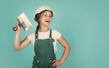 Ev tadilatı. Aletli çocuk. Spatulalı mutlu küçük inşaatçı kız. Genç kız macun bıçağı kullanıyor. Tulumlu ve spatulalı miğferli bir müteahhit. Çocuk duvar macunuyla onarıyor. Boşluğu kopyala