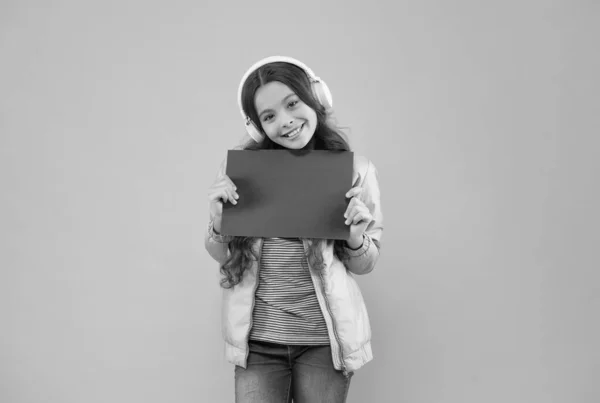 Menina feliz adolescente ouvir música em fones de ouvido apresentando papel vazio, tecnologia — Fotografia de Stock