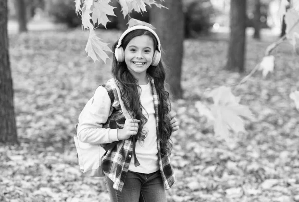 Criança sorrindo levar mochila e ouvir música, tempo de escola — Fotografia de Stock