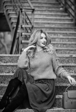 Ilık sonbahar. Sonbahar moda trendi. Giyilebilir trendler. Kız eteğinin üstüne daha büyük bir katman örülmüş. Sonbahar formülü. Sonbahar için stil süveter ve etek karışımı. Muhteşem kadın saç stili merdivenlerde oturuyor.