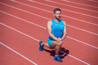 Her zaman formdadır. Sporcu dışarıda kaslarını esnetiyor. Kaslı adam esneme hareketleri yapıyor.