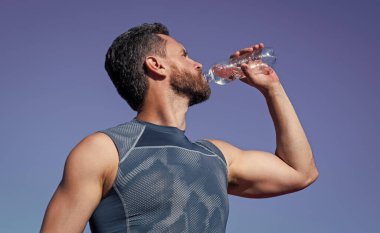 Adamın suya ihtiyacı var. Spor ve sağlıklı yaşam tarzı rutini. Vücuttaki su dengesi. Sporcu egzersizden sonra susar. Sporcu şişeden içiyor. Sağlık hizmeti. Kaslı adam spor üstüne su içiyor.