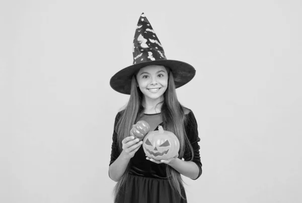 Cree en la magia. un niño adolescente con sombrero de bruja. niño alegre sosteniendo la calabaza. fiesta de disfraces de carnaval. truco o trato. celebrar las fiestas. Jack o Linterna. Chica bruja de Halloween. feliz infancia — Foto de Stock