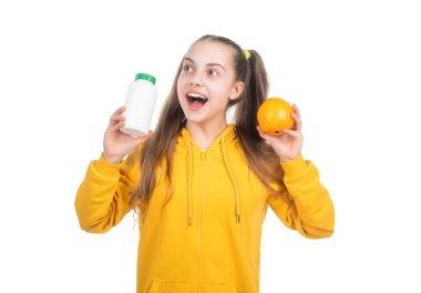 Şaşırmış çocuk portakal meyvesi ile vitamin hapı arasında seçim yapıyor..