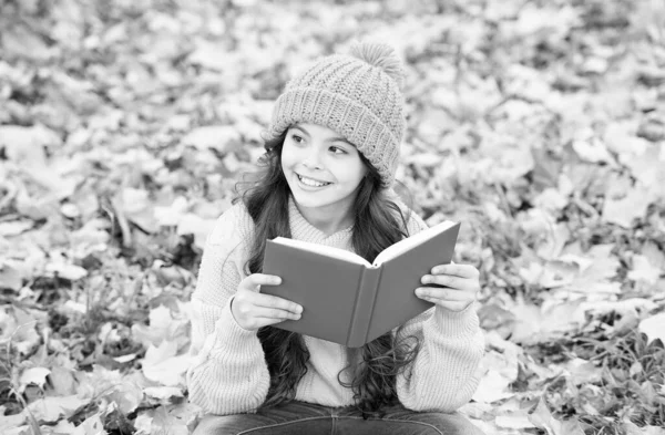 La conoscenza è seme che cresce quando leggi. Il bambino felice legge il libro seduto su foglie di autunno. Giorno della conoscenza. 1 settembre. Istruzione primaria. Biblioteca scolastica. Pagina per pagina non c'è bisogno di aspettare — Foto Stock