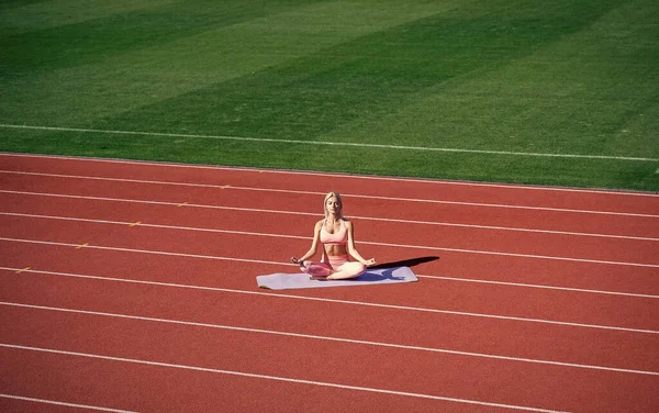 Fit lady w stroju fitness medytacja na stadionie po treningu sportowym, joga — Zdjęcie stockowe