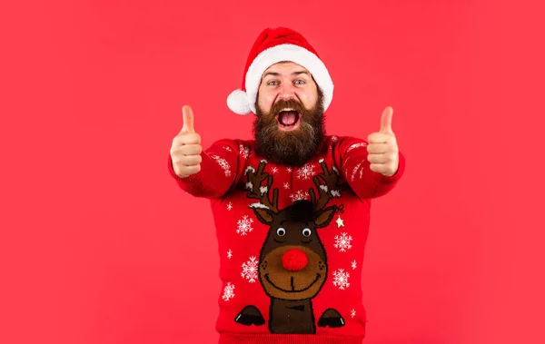 Thumb up for success. brutal bearded male red background. party man in Christmas sweater. happy caucasian guy await new year present. lets have fun. Santa Claus hipster. handsome man at Christmas — Stock Photo, Image