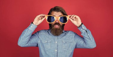 Beyaz tenli, sakallı, şık saçlı, gözlüklü bir hippi.