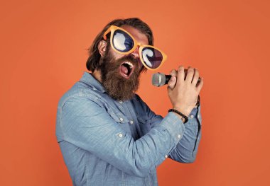 Kalbinin ritmine göre şarkı söyle. Müzik konsepti. Oyuncu eğleniyor. Komik parti gözlüklü olgun sakallı adam şarkı söyler. Mikrofonlu vahşi erkek hippi. vokal okulu. favori müzik tarzı