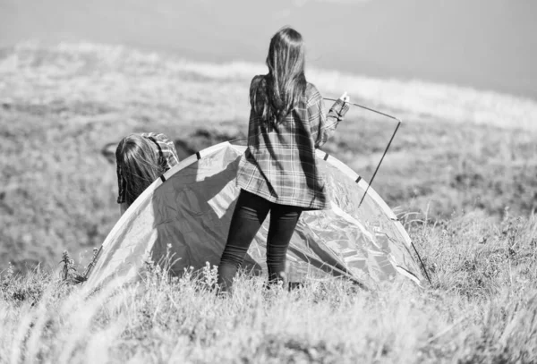 Camping vandring. Hjälpsam att ha partner för att höja tältet. Kvinnor sätter upp tält på toppen berg. Vandringsaktivitet. Fäst nödvändiga konstruktionskomponenter tält. Förbered dig för natten. Tjejscoutkoncept — Stockfoto