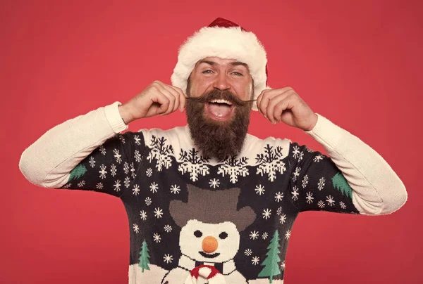 Vrolijk baard man aanraken snor dragen grappig gebreide trui en kerstman hoed voor het vieren van kerstvakantie, kerstdag — Stockfoto