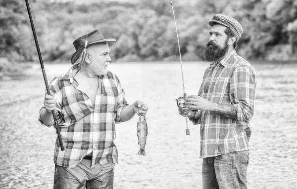 Loisirs fous. Temps de pêche à la mouche. hobby. Camping sur la rive du lac. Pêche au gros. amitié. deux pêcheurs heureux avec canne à pêche et filet. tourisme de chasse. père et fils pêche — Photo