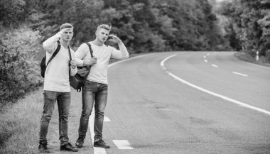 Bütçe yolcuları. Sırt çantaları yolda beraber yürüyorlar. Yol boyunca yürüyen ikizler. Macera ve keşif. Sırt çantalı bir adam yolda otostop çekiyor. Yaz tatili. Turist gezgini otomobil durağında.