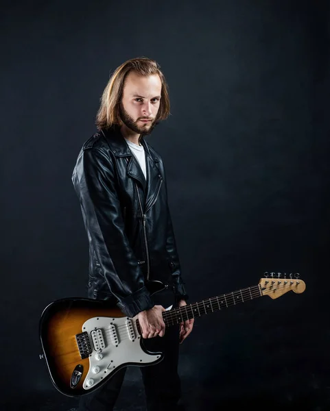 Szakállas rockzenész elektromos gitározik bőrdzsekiben, zenész — Stock Fotó