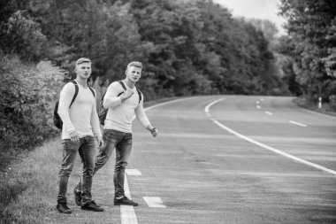 İnsanların otostopçuları alma sebebi. Otobüslerini kaçırdılar. Yardıma ihtiyacım var. Ucuz ulaşım. Taşıma sorunu. Seyahat ve taşıma konsepti. Yolun kenarında duran ikiz adamlar. Bir araba durdurmayı dene.