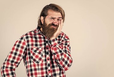 Bıyıklı, vahşi beyaz adam. Sakallı adam kareli gömlek giyer. Acıdan kıvranan acımasız adam. Erkek sağlık hizmetleri. Dişlerin ağrıyor. Sakallı olgun bir hippi diş ağrısı çekiyor.