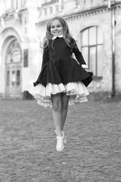 Energisk liten unge i elegant uniform klänning hoppa i skolgården utomhus, skolgång — Stockfoto