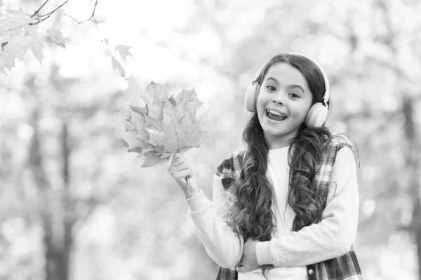 Gelukkig kind in casual stijl tijd doorbrengen in de herfst bos met esdoorn bladeren genieten van goed weer tijdens het luisteren muziek in hoofdtelefoon, online onderwijs — Stockfoto