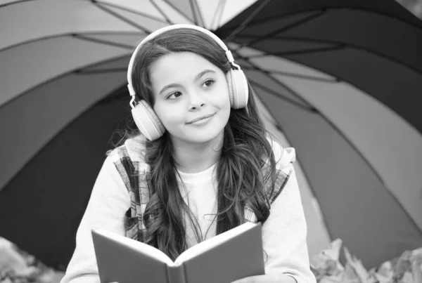 Fröhliche Mädchen in lässigem Stil verbringen Zeit mit Musik hören und Buch lesen im Herbst Park genießen gutes Wetter unter bunten Regenschirm, zurück zur Schule — Stockfoto