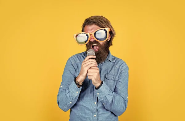 Hipster caucasico con barba e capelli eleganti in occhiali artistici con microfono, musica — Foto Stock