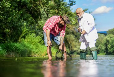 Emekli baba ve olgun sakallı oğul. Yakalama ve balık tutma konsepti. İki erkek arkadaş birlikte balık tutuyor. Mutlu balıkçı arkadaşlığı. İş adamının uçan balık hobisi. emeklilik balıkçılığı. Birlikte eğleniyoruz.