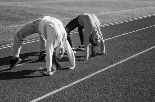 Flexibele meisjes gymnasten staan in krab positie op atletiek track, flexibiliteit — Stockfoto