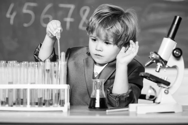 Kleine jongen met microscoop op school les. resultaat. Medisch concept. Klein geniaal kind. het testen van buizen met vloeistof voor onderzoek. leren voor de toekomst. Biologie wetenschap. kleine jongen studie chemie — Stockfoto