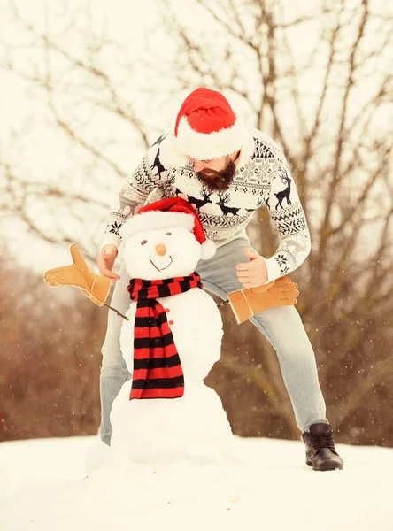 Muy bien. hombre barbudo construir muñeco de nieve. actividad de temporada de invierno. es navidad. vacaciones de invierno al aire libre. suéter caliente en clima frío. hombre santa sombrero jugar con la nieve. feliz hipster listo para celebrar la Navidad — Foto de Stock