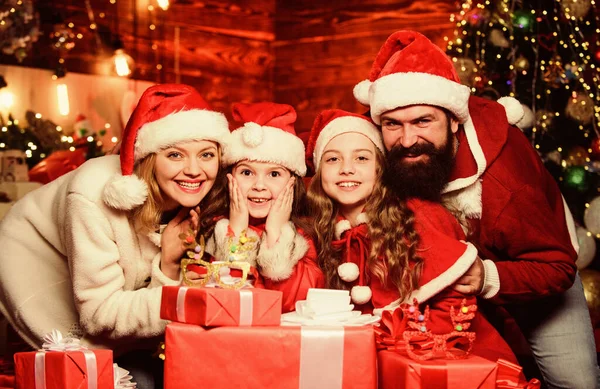 クリスマスの魔法だ。メリー・クリスマス。父と母は子供が大好きです。多くのxmasプレゼントボックス。サンタ・ハットの小さな子供と両親。家族を愛する肖像画。幸せな家族は新年を祝う — ストック写真
